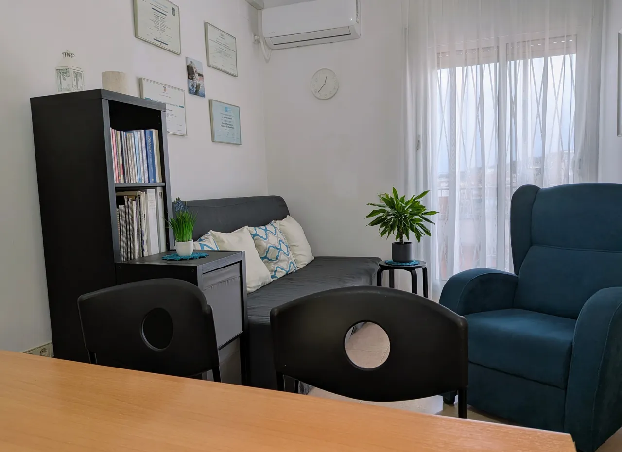 Consulta de psicología en Barcelona con sofá, estantería y diplomas
